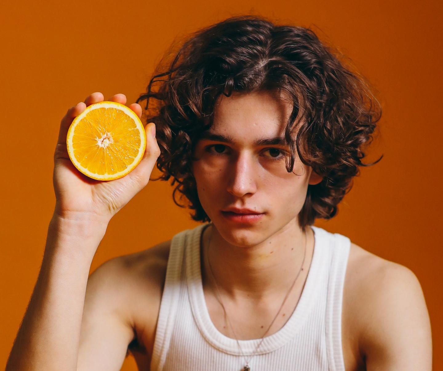 Curly-haired individual with citrus, representing vitamin-rich hair care.